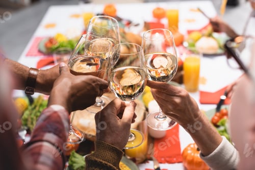 Preview: partial view of multiethnic relatives clinking wine glasses while celebrating thanksgiving day