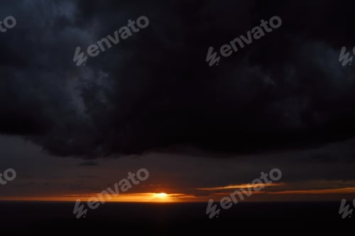 Preview: Orange streak of sunset on a dark stormy sky
