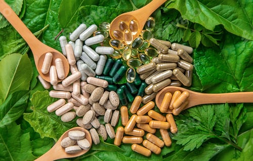 Preview: Capsules herb supplements on green leaves background. Selective focus.