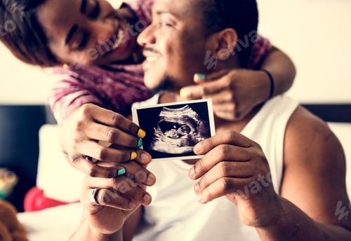 Preview: Black couple showing baby ultrasound scan photo