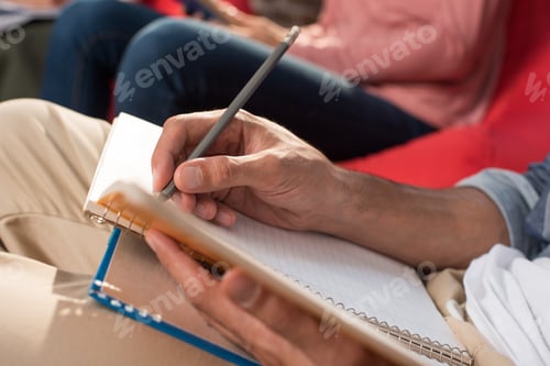 Preview: cropped view of student with copybook and book studying at home