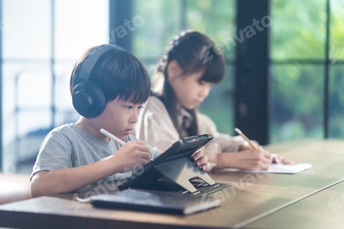 Preview: Asian children self learning at home. The boy using tablet and headphones for E-learning at home.