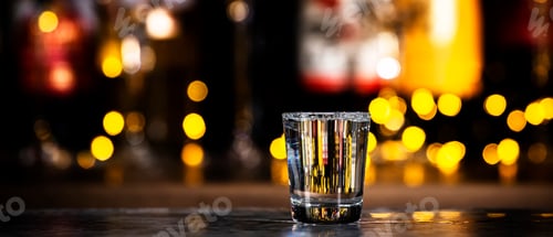 Preview: Vodka in glass and bottles of strong drinks on black bar background with lights