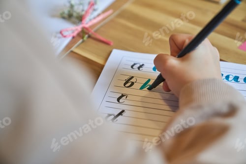 Preview: Crop unrecognizable artist drawing letters sitting at wooden table