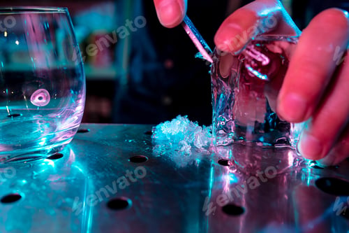 Preview: Close up of barman crushing a big piece of ice on the bar counter with a special bar equipment on it