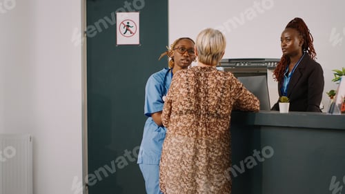 Preview: Team of medical workers talking at clinic reception counter