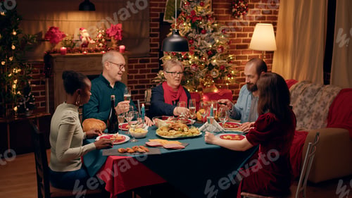 Preview: Laughing diverse people gathered around Christmas dinner table clinking wine glasses