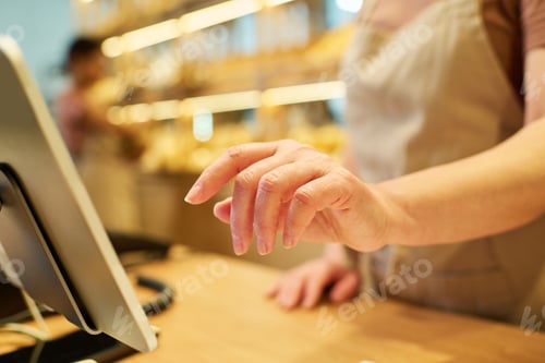 Preview: Selective focus on hand of mature female clerk entering prices of products