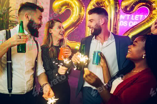 Preview: Multiracial people with sparklers and drinks celebrating new years eve in the club
