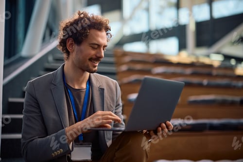 Preview: Smiling entrepreneur working on a computer at conference hall.