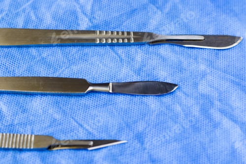 Preview: Closeup of sterile medical scalpels on a blue surface in the hospi