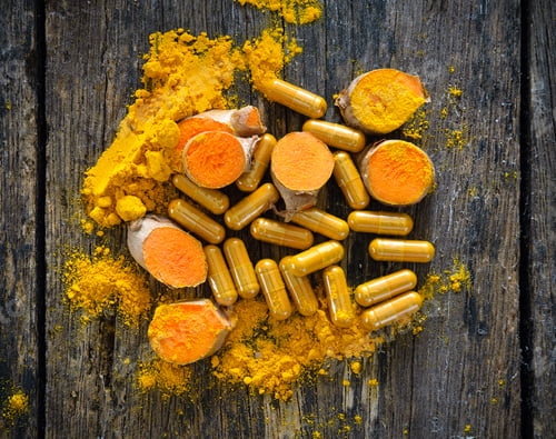 Preview: Turmeric powder and turmeric capsules on wooden background