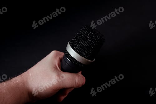 Preview: Closeup shot of a microphone in the hand of a person on a black background