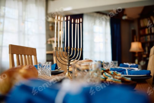 Preview: Lit candles in menorah on Hanukkah table setting.