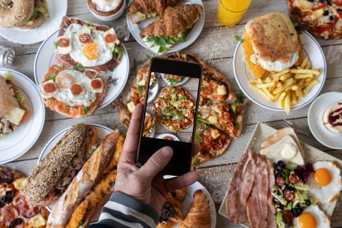 Preview: Person photographing a diverse brunch spread with smartphone