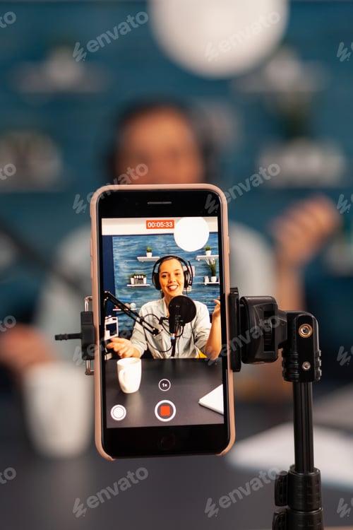 Preview: Close up of influencer vlogger record video live broadcast looking at smartphone on tripod at home