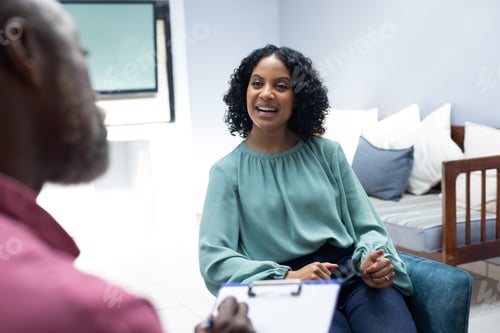 Preview: Happy biracial female patient attending therapy with african american male therapist