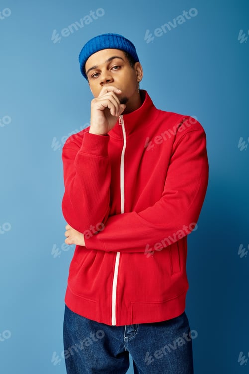 Preview: Trendy young african american man with beanie hat against a vibrant blue backdrop