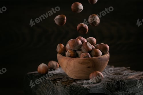 Preview: Pile of hazelnuts filbert in a wooden bowl on a dark wooden background.