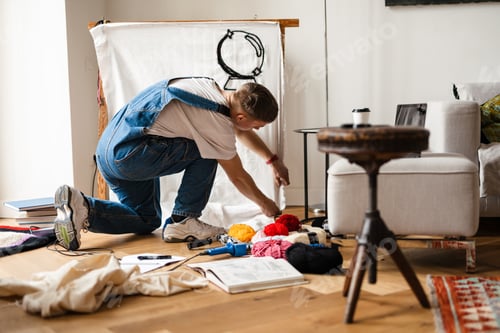 Preview: Young white man wearing overall working on craft rug at home