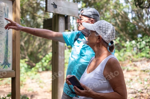 Preview: Carefree couple of senior man and woman in a trekking day in the forest enjoying healthy lifestyle