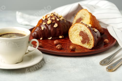 Preview: Chocolate croissant on clay plate with cup of coffee on table