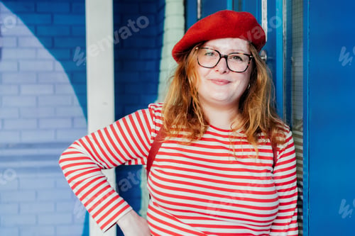 Preview: Young smiling fashion plus size woman in bright clothes posing on painted brick background.
