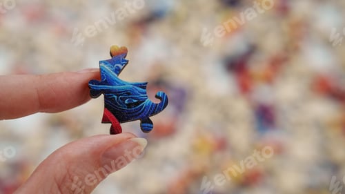 Preview: Place for text. A hand holds a wooden blue puzzle. Advertising photo of unique puzzles.