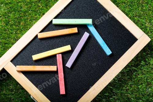 Preview: Top view of mini blackboard and colors on plastic grass background. Concept back to school