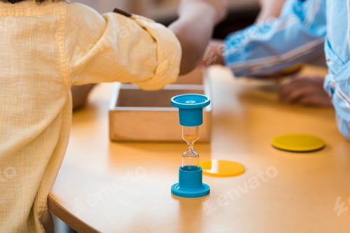 Preview: Selective focus of kids with educational game and hourglass at desk in montessori school