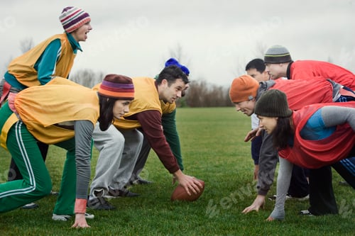 Preview: Caucasian woman playing quarterback for a team of friends playing non-contact flag football.