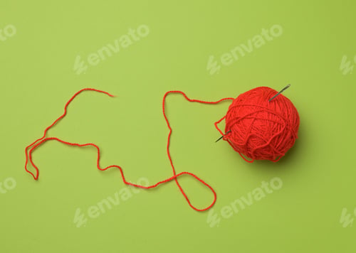 Preview: Clew with red-woolen thread on a green background