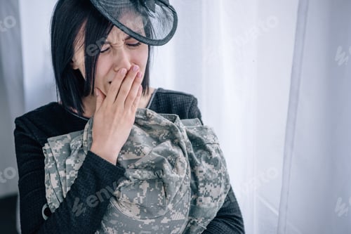 Preview: upset crying woman holding military clothing at home