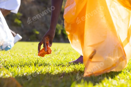 Preview: Picking up trash, african american girl in school uniform cleaning up grassy field