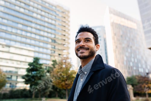 Preview: Portrait of young adult Latin American businessman smiling at city street