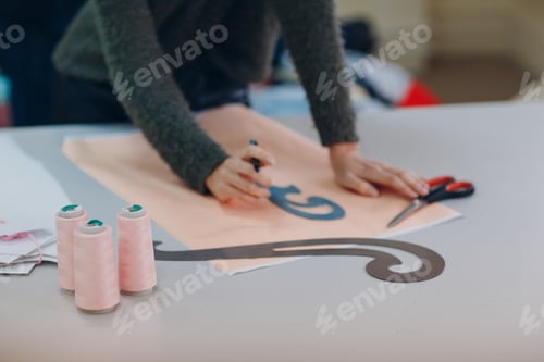 Preview: Young beautiful seamstress cutter clothing designer with pattern and template in garment factory