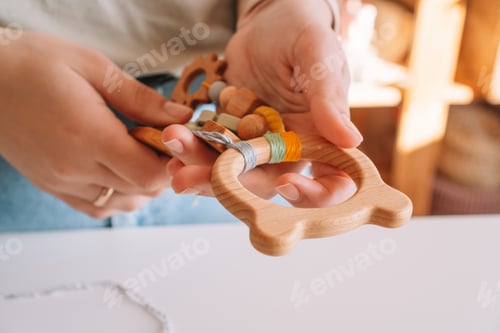 Preview: Cropped woman hands holding handmade ecological teether like bear toy with trinket rattle decoration