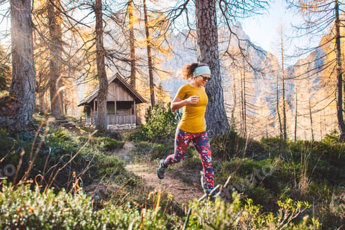 Preview: Cheerful caucasian woman on a hike running trough the autumn forest, sun rays shining trough the