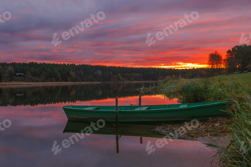 Preview: A Serene Sunset Over Calm Waters Featuring a Charming Green Boat Floating Gracefully. Birstonas