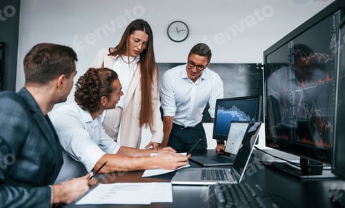 Preview: Attention to details. Team of stockbrokers works in modern office with many display screens