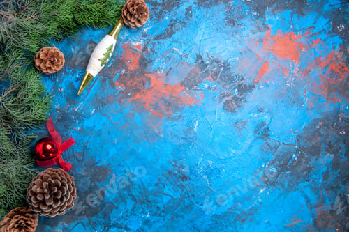 Preview: top view pine tree branches with pinecones xmas toys on blue-red background with free space