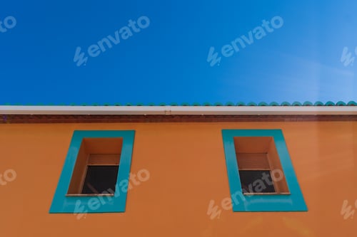 Preview: blue window frames on orange colored house facade with green tiled roof
