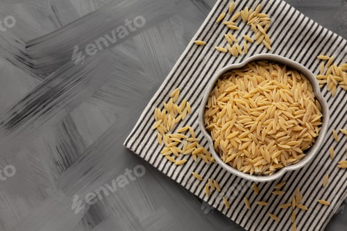 Preview: Raw Organic Orzo Pasta in a Bowl, top view. From above, overhead, flat lay.