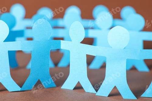 Preview: Paper figures of people holding hands on brown background, closeup