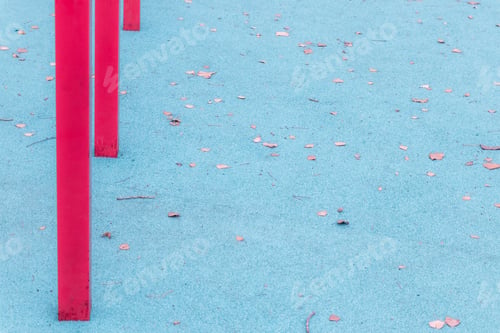Preview: Blue rubber playground with red bars and fallen leaves: Active outdoor fun among triangular shapes.