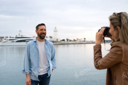 Preview: girl taking a photo of a boy while they are on vacation in Malaga