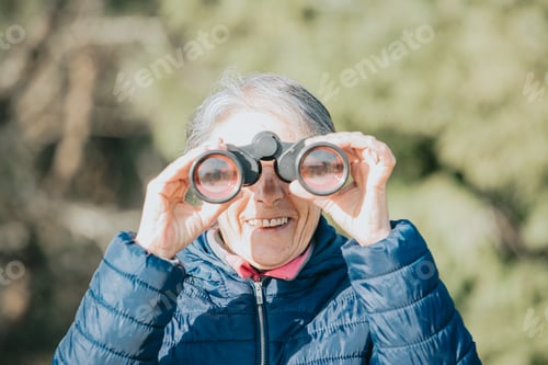 Preview: Super happy smiling old woman learning to use scouts during a nature walk, new hobby