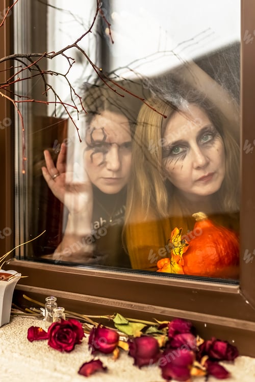 Preview: Two witches look through of the window of Halloween decorations. Masquerade, Halloween party