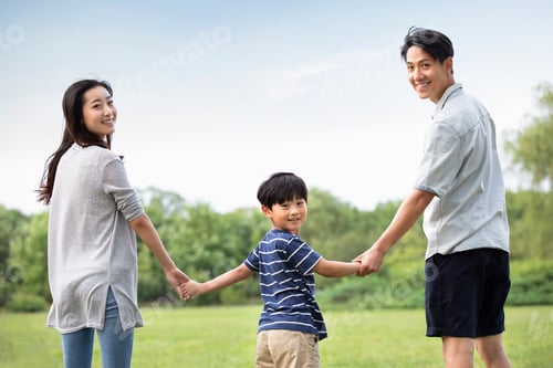 Preview: Happy young Chinese family holding hands on grass
