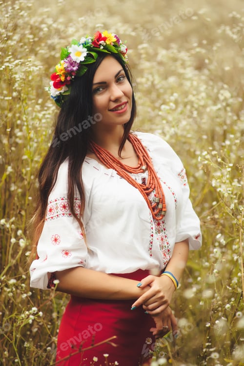 Preview: Beautiful Ukrainian woman in traditional costume in flowers field